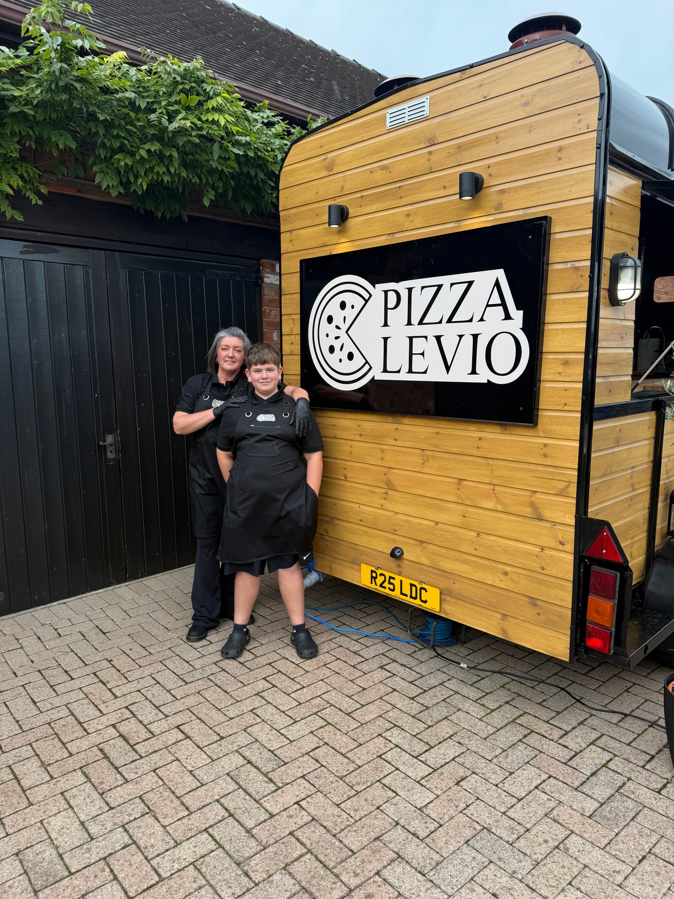 The Pizza Levio team beside their timber-clad pizza trailer